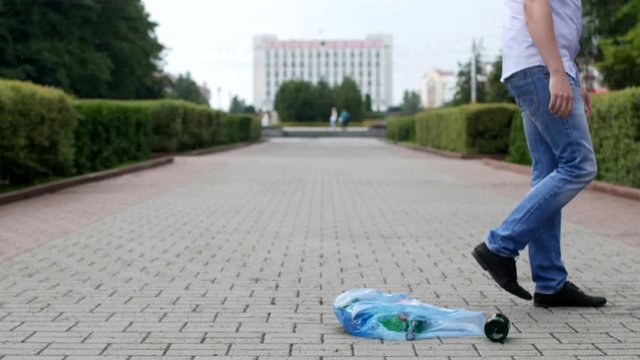 A young man throws out a package of garbage in the center of the city, litterbug