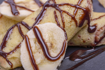crepe with banana and chocolate on round slate stand