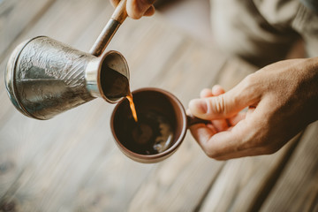 Man pouring hot coffee from turk