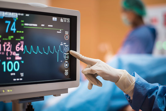 Electrocardiogram in hospital surgery operating  emergency room showing patient heart rate with blur team of surgeons background   