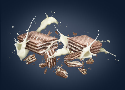 Wafers are broken into pieces, with a dairy splash, against a dark background