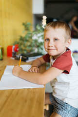 Photo of boy with pen and notebook sitting at table