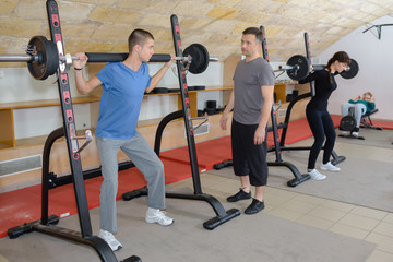 Fototapeta na wymiar teen training with weights at gym club with coach