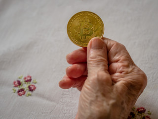 Alte Frau hält physische Bitcoin Münze in der Hand