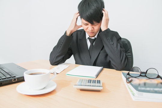 Asian young man in black suit are stress worry probleme working sitting on chair in office.