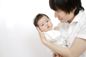 父に抱かれ見つめられる新生児の女の子