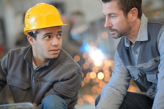 male supervisor discussing with manual worker in metal industry