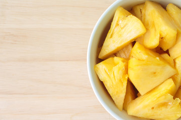 Pineapple on a plate placed on a wooden table.