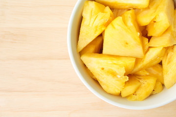 Pineapple on a plate placed on a wooden table.