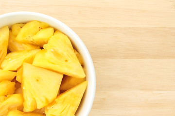 Pineapple on a plate placed on a wooden table.