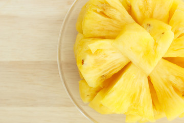 Pineapple on a plate placed on a wooden table.