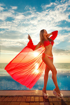 Summer Vacation. Silhouette of beauty dancing woman on sunset near the pool with ocean view. Beach at the blue sea.