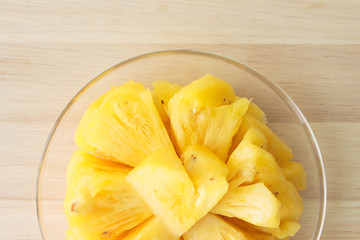Pineapple slice on a plate placed on a wooden table.