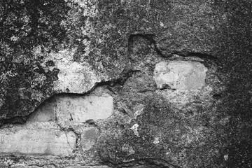 Damaged old grunge wall with bricks showing through.