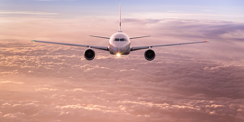 Fototapeta premium Komercyjny samolot latający nad dramatyczne chmury podczas zachodu słońca.