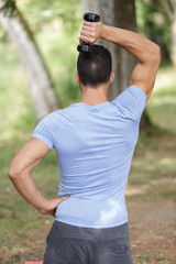 muscular bodybuilder man doing exercises in outdoor