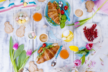 Easter breakfast flat lay with, bread toast with fried egg and gre, colored quail eggs and spring holidays decorations. Top view. Copy space. croissants for breakfast. Free space for text or postcard
