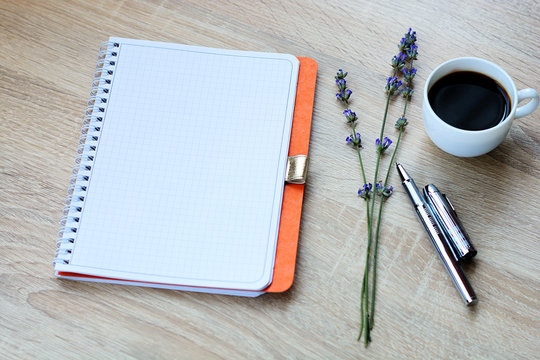 Open notebook, coffee mug, fountain pen and flowers (lavender) on the desktop. 