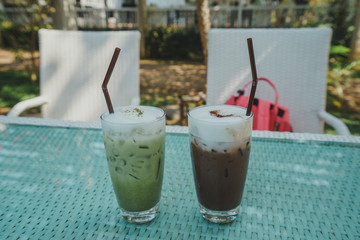 Ice green tea and Ice chocolate with milk foam on the table.