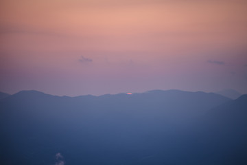 A pastel sunset panorama of mountains in the winter.
