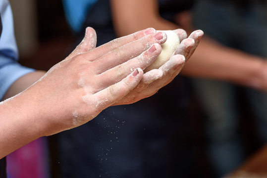 Close-up of children's hands preparing dough for pizza