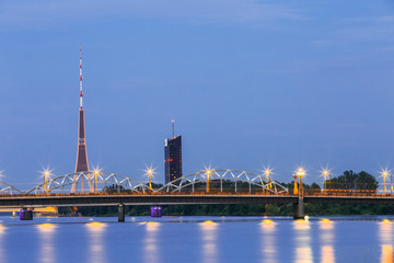 Fototapeta na wymiar Riga Latvia. Illuminated Two Bridges: Stone And Railway Bridge With Red Radio TV Tower Background
