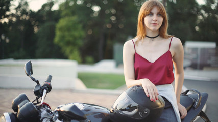 Fototapeta na wymiar beautiful young red-haired woman motorcyclist with black motorcycle helmet