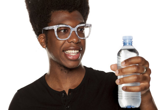 Portrait of young african american man holding plastic bottle of water on white background