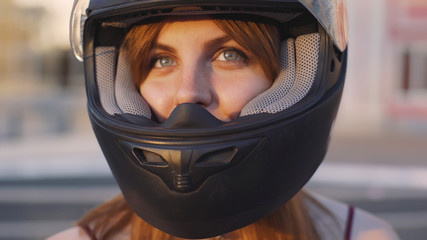 beautiful young red-haired woman motorcyclist with black motorcycle helmet