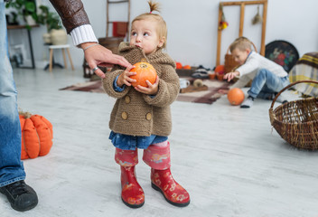 Fototapeta premium The father gives a hand to the little daughter with pumpkin in hands in interior