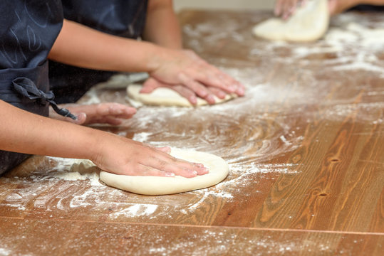 Close-up of children's hands preparing dough for pizza