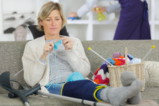 cheerful injured woman knitting on the sofa