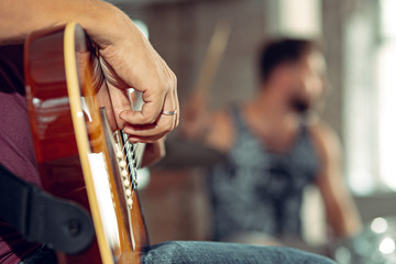 Repetition of rock music band. Electric guitar player and drummer behind the drum set.