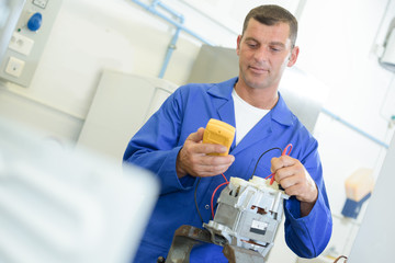 Man testing electrical component with multimeter - obrazy, fototapety, plakaty