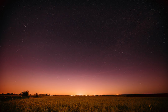 Natural Night Starry Sky Above Summer Field Meadow. Glowing Stars