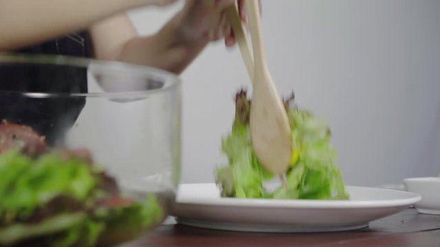 Close up of Health conscious young chief woman tossing a tasty organic green salad.
