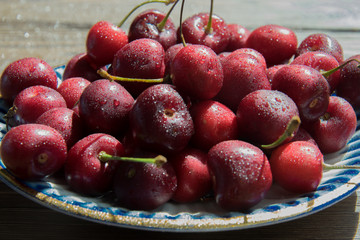 Cherry berries in a blue gzhel plate on a  wooden background