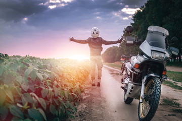 motorcycle driver stands with his arms outstretched. for a meeting of adventures on the dirt road...