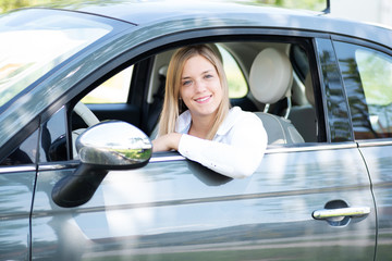 Junge Autofahrerin sympathisch lächelnd am Steuer ihres Wagens 