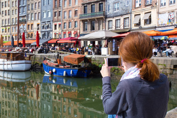 Fototapeta na wymiar girl taking a shot of Honfleur harbor