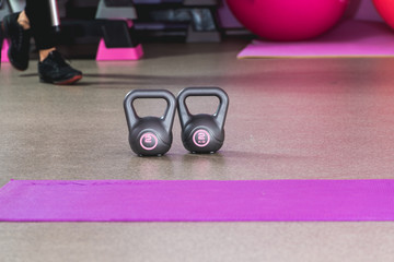 Two kilos in a grey colour weights in a sport studio with pink balls on the backround and sneakers