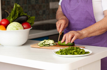 Cropped image of old woman cutting vegetables in the kitchen. Healthy food.