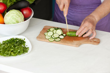 Cropped image of old woman cutting vegetables in the kitchen. Healthy food.