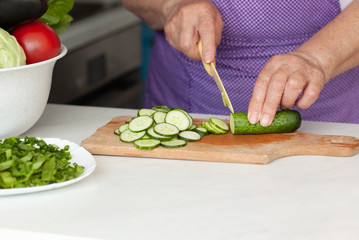 Cropped image of old woman cutting vegetables in the kitchen. Healthy food.