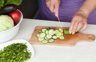 Cropped image of old woman cutting vegetables in the kitchen. Healthy food.