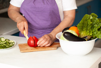 Cropped image of old woman cutting vegetables in the kitchen. Healthy food.