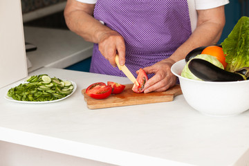 Cropped image of old woman cutting vegetables in the kitchen. Healthy food.