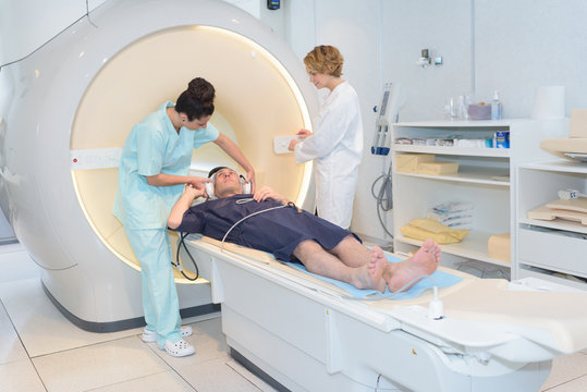 Nurse putting ear protectors on patient for mri scan
