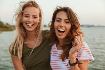 Women friends hugging outdoors on the beach.