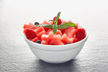 Salad of fresh juicy pieces of watermelon, raspberry and currant with green mint leaves